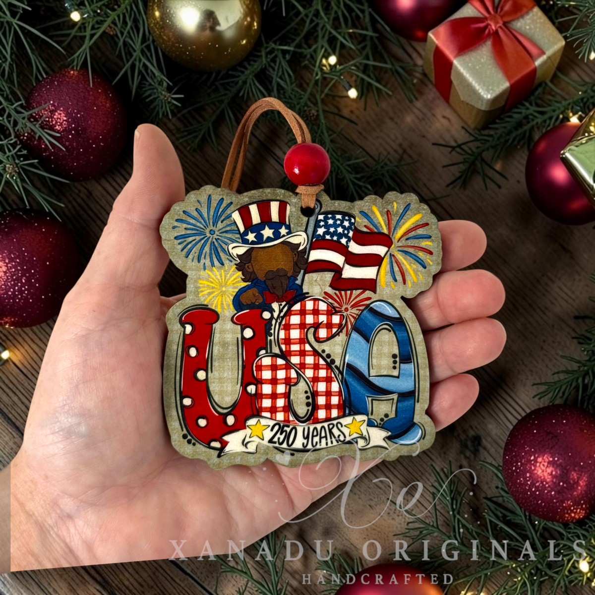 Retro patriotic Uncle Sam 250 Years USA Christmas ornament measuring 3.45 by 3.45 inches held in a hand next to holiday tree decorations.
