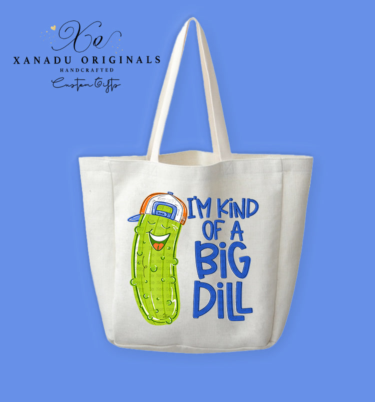 A cream-colored polyester linen tote bag featuring a bright cartoon illustration of a smiling pickle character wearing a backwards baseball cap next to the blue text "I'M KIND OF A BIG DILL".