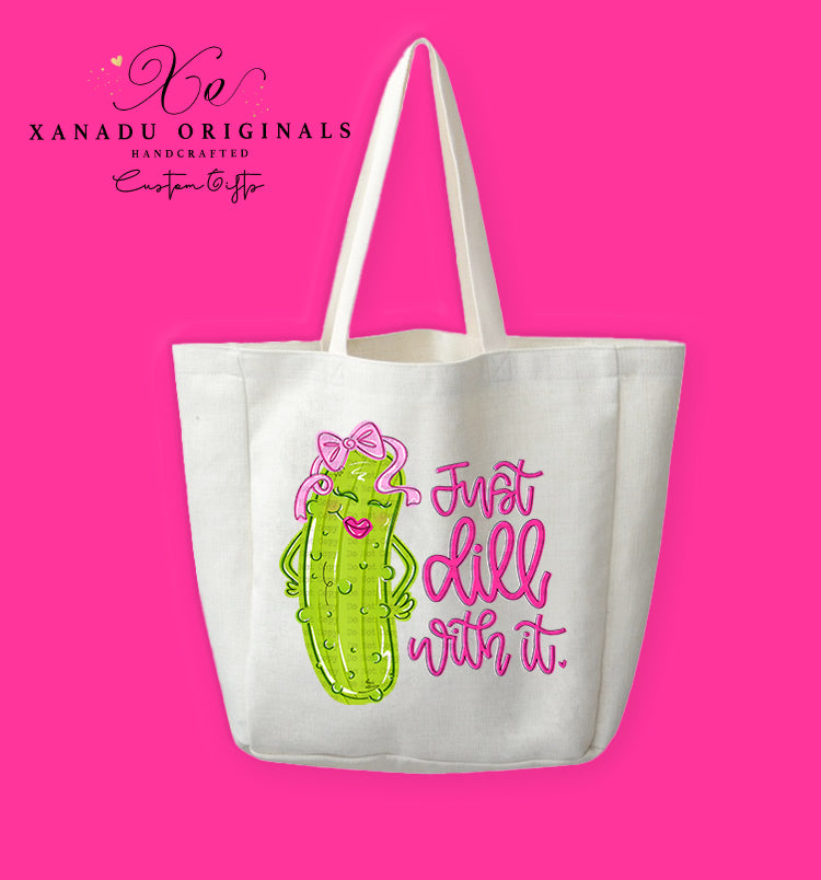 A cream-colored polyester linen tote bag featuring a cute cartoon illustration of a girly pickle character wearing a big pink bow next to the script text "Just dill with it."