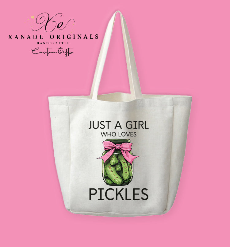 A cream-colored polyester linen tote bag featuring a clear jar of dill pickles decorated with a big pink ribbon bow between the text "JUST A GIRL WHO LOVES PICKLES".