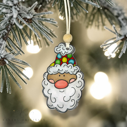 A close-up shot of a light skin tone Santa wood ornament with a multi-colored polka dot hat hanging from a frosted pine branch against a warm, glowing holiday light backdrop.
