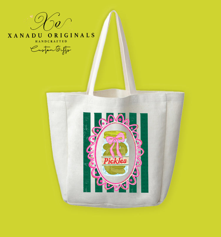 A cream-colored polyester linen tote bag featuring a retro graphic of a pickle jar with a pink bow inside an ornate lace frame against dark green vertical stripes.