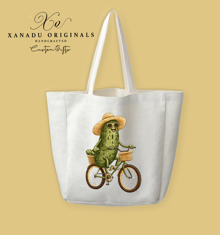 A cream-colored polyester linen tote bag featuring a detailed illustration of a smiling green pickle wearing a straw hat and sunglasses while riding a bicycle with a basket.