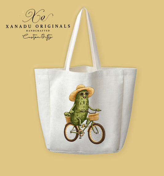 A cream-colored polyester linen tote bag featuring a detailed illustration of a smiling green pickle wearing a straw hat and sunglasses while riding a bicycle with a basket.