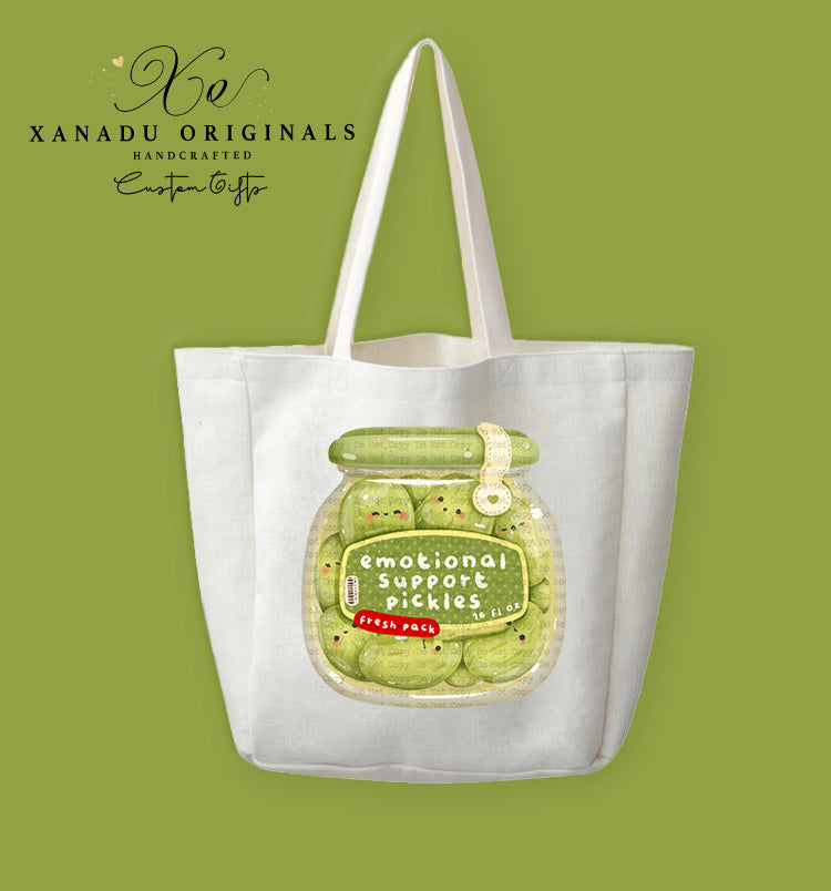 A cream-colored polyester linen tote bag featuring a cute kawaii illustration of a glass jar filled with tiny smiling pickle slices labeled "emotional support pickles".