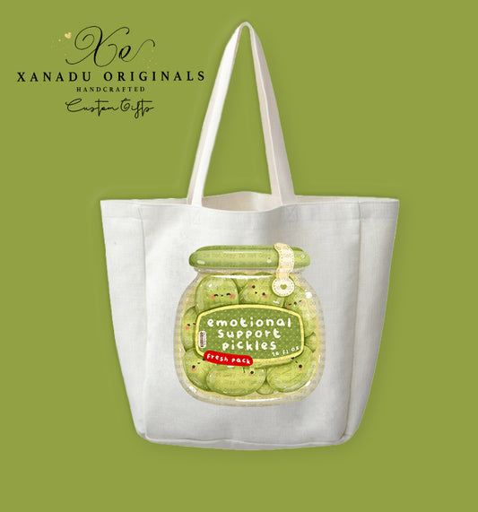 A cream-colored polyester linen tote bag featuring a cute kawaii illustration of a glass jar filled with tiny smiling pickle slices labeled "emotional support pickles".