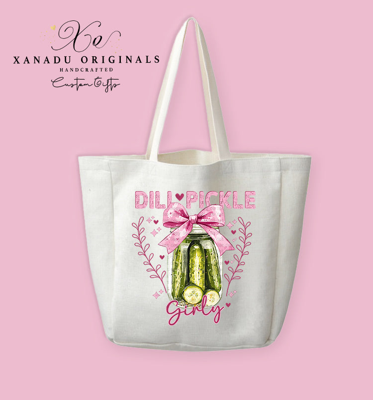 A cream-colored polyester linen tote bag featuring a watercolor illustration of a glass jar of dill pickles decorated with a large pink bow, leafy vines, and the text "DILL PICKLE Girly" in pink lettering.