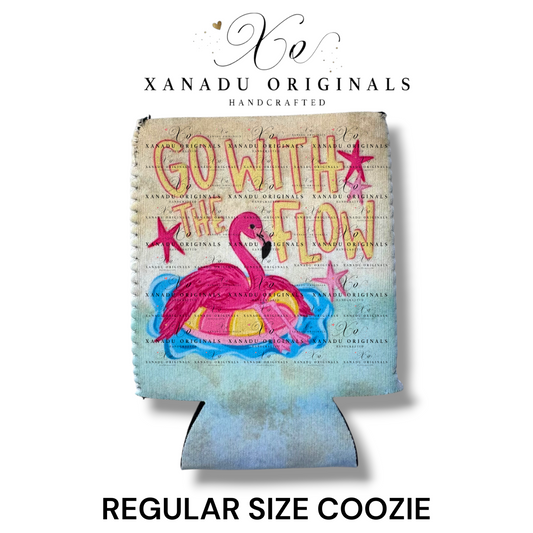 "Xanadu Originals handcrafted regular size neoprene can coozie featuring a colorful illustration of a pink flamingo floating in a yellow inner tube on pool water with the text 'GO WITH THE FLOW' and pink starfish on a textured canvas background."