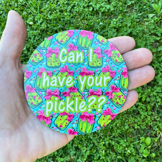 3.6 inch round circular MDF wood coaster featuring a repeating pattern of green pickles with bright pink bows and scattered dots on a turquoise blue background, with central text reading Can I have your pickle??