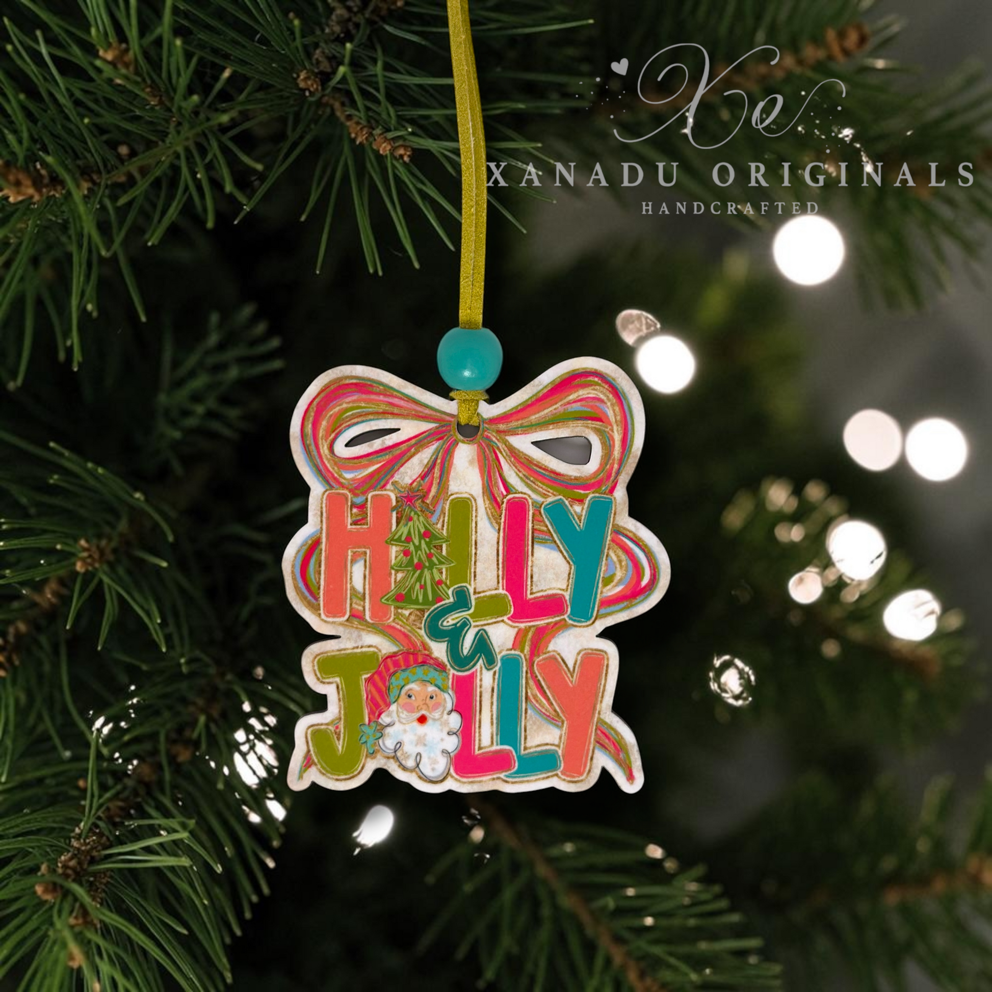 Handcrafted wooden Christmas ornament hanging on a pine tree, featuring a bow, colorful 'Holly & Jolly' lettering, and a small Santa illustration. The ornament has a green hanging string and a turquoise bead at the top.
