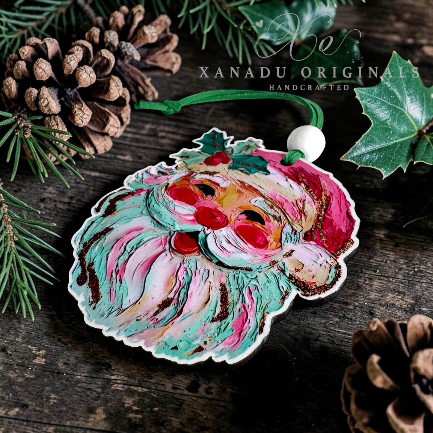 Handcrafted wooden Christmas ornament featuring a stylized Santa face with swirling teal, pink, cream, and brown painted details, hanging on a rustic dark wood surface with pinecones, evergreen branches, and holly leaves. A white bead loop and green string are visible at the top.