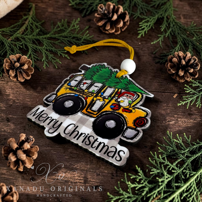 A handcrafted Christmas ornament shaped like a yellow jeep carrying a green Christmas tree, with Santa visible in the driver's seat. The ornament has a yellow hanging cord, a white bead, and the words 'Merry Christmas' in black script on a white plaid section.