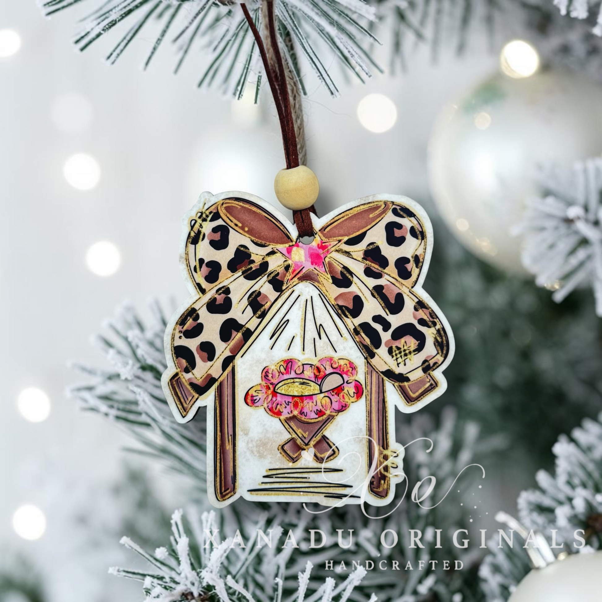 Decorative Christmas ornament by Xanadu Originals, featuring a leopard print bow, a pink and gold star on a flocked christmas tree branch.