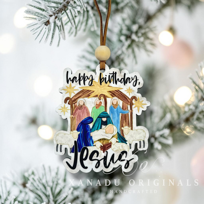 Decorative wooden Christmas ornament with nativity scene and 'Happy Birthday Jesus' text, hanging on a tree.