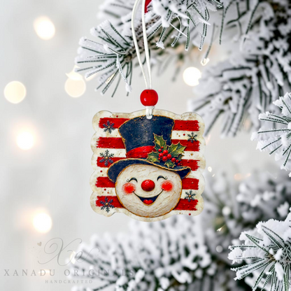A handcrafted wooden Christmas ornament shaped like a smiling face wearing a striped red and white top hat, hanging from a white string on a snowy flocked Christmas tree branch with warm bokeh lights in the background.