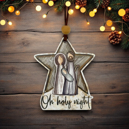 A handmade Christmas ornament card featuring a star-shaped nativity ornament with two figures and a baby, hanging from a wooden bead. The ornament reads 'Oh holy night' and is styled on a rustic wood surface.