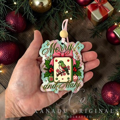 Whimsical game lover Mahjong Christmas ornament measuring 2.97 by 3.6 inches held in a hand next to holiday tree decorations.