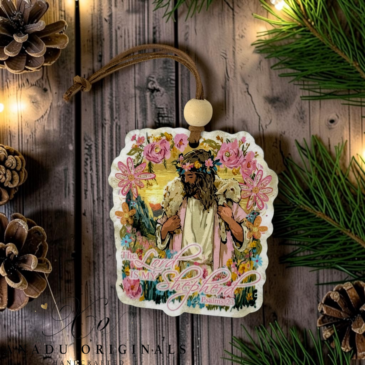 The Lord Is My Shepherd wood ornament featuring a colorful folk art illustration of Jesus as the Good Shepherd with a lamb, mountain sunset, and pink roses.