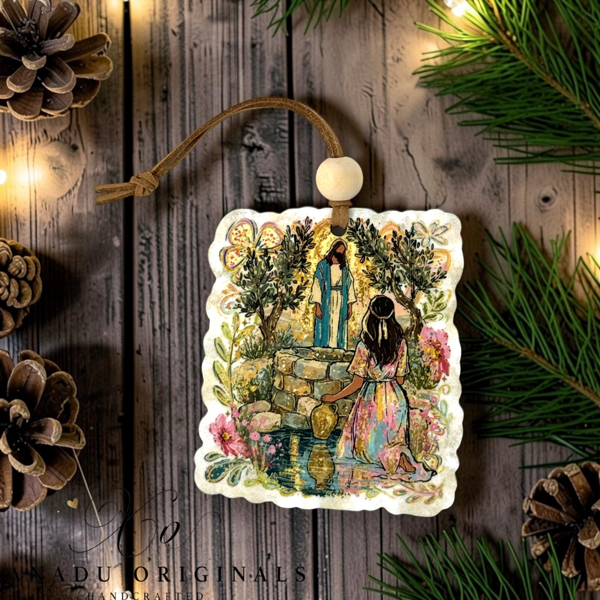 Woman at the Well wood ornament featuring a colorful folk art illustration of Jesus meeting a woman in a pink dress at a stone well surrounded by olive trees.