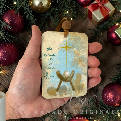 Retro Christian manger scene ornament measuring 2.71 by 3.9 inches being held in a hand next to holiday tree branches and red ornaments.