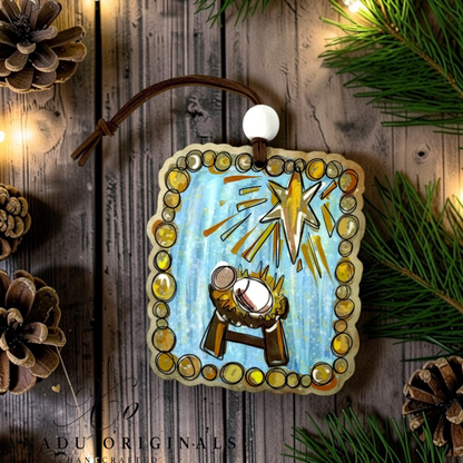 Painted style baby Jesus manger wood ornament featuring a sleeping Christ child beneath a radiating gold star with an amber painted bubble frame layout.