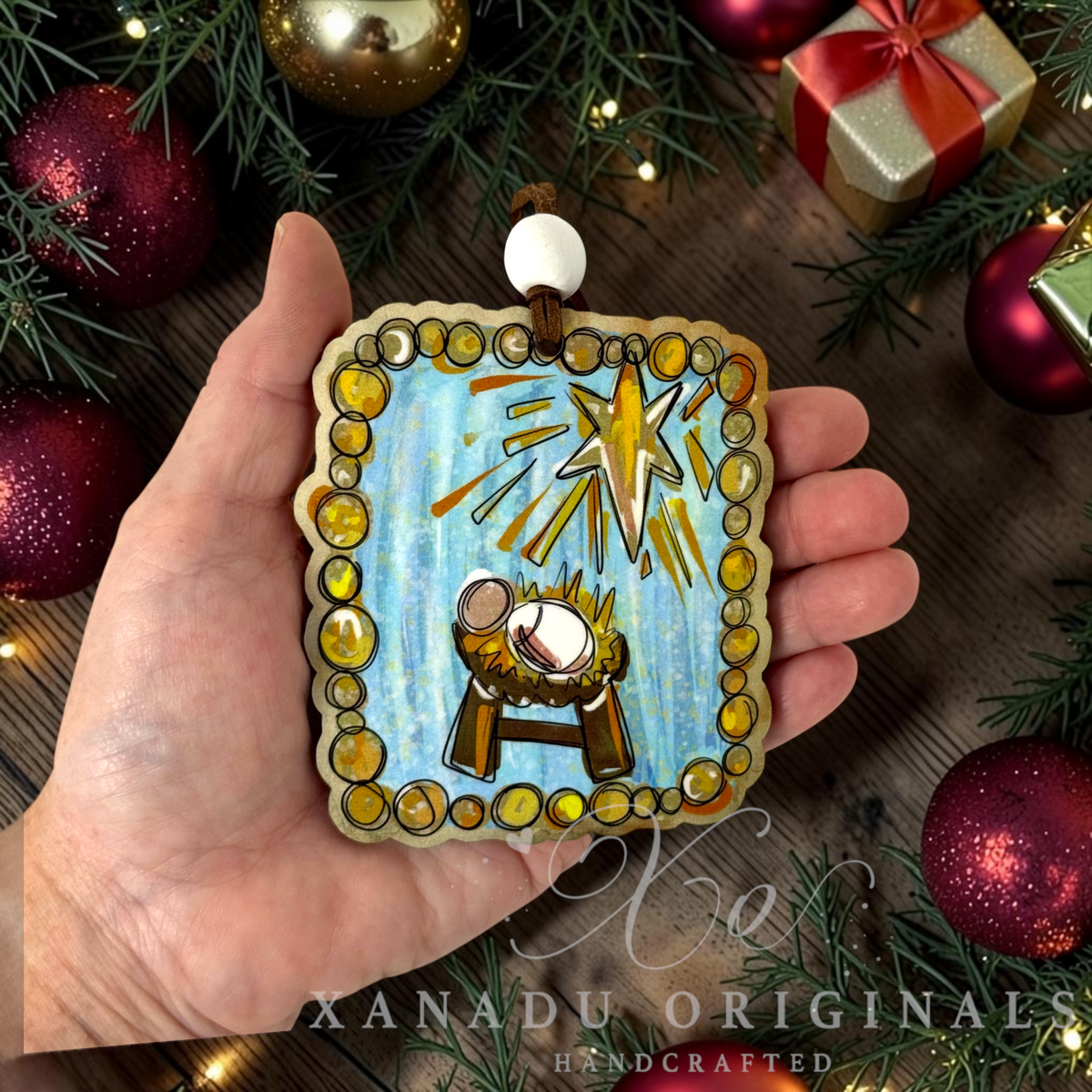 Retro Christian painterly nativity ornament measuring 3.25 by 3.67 inches held in a hand next to festive holiday decorations.
