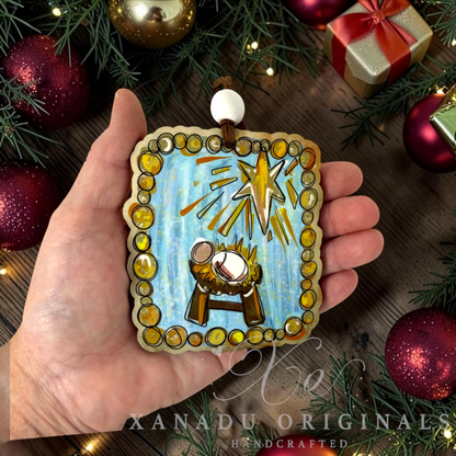 Retro Christian painterly nativity ornament measuring 3.25 by 3.67 inches held in a hand next to festive holiday decorations.
