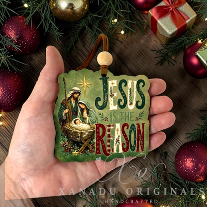 Retro religious Christmas nativity ornament that says Jesus Is The Reason  measuring 3.45 by 3.39 inches held in a hand next to holiday tree decorations.