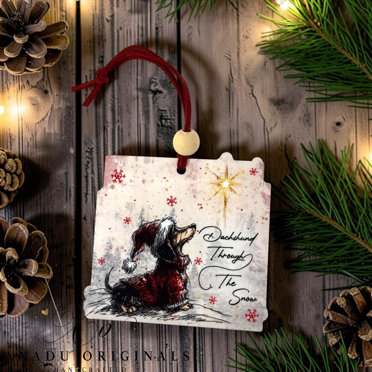 Dachshund Through the Snow wood ornament featuring a sketchy style long haired dog in a red coat and Santa hat under a gold star with cursive holiday text.