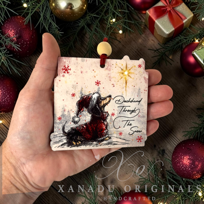 Whimsical pet lover Dachshund Christmas ornament measuring 3.5 by 3.38 inches held in a hand next to holiday tree decorations.