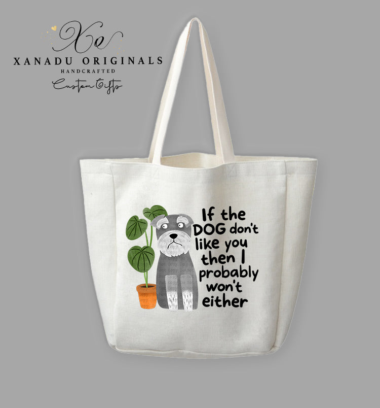 A cream-colored polyester linen tote bag featuring a cartoon illustration of a wide-eyed grey Schnauzer dog sitting next to a green plant in an orange pot. Bold black text to the right reads "If the DOG don't like you then I probably won't either."