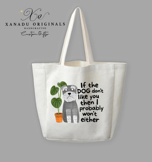 A cream-colored polyester linen tote bag featuring a cartoon illustration of a wide-eyed grey Schnauzer dog sitting next to a green plant in an orange pot. Bold black text to the right reads "If the DOG don't like you then I probably won't either."