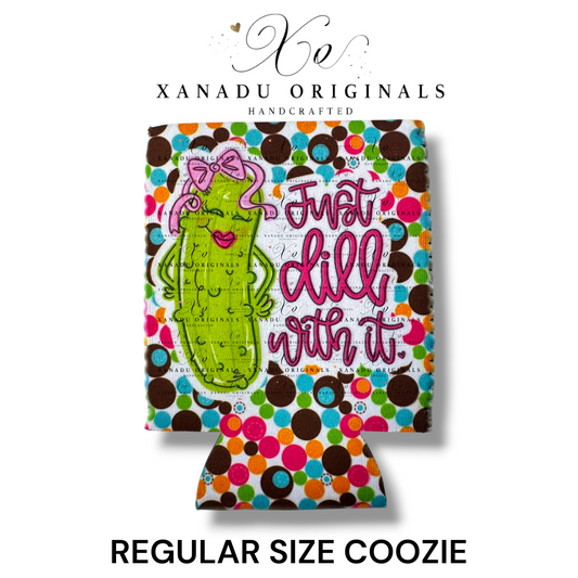 "Xanadu Originals handcrafted regular size neoprene can coozie featuring an illustrated sassy cartoon pickle with a pink bow and lipstick beside the pink script text 'Just dill with it.' over a vibrant retro multi-color polka-dot background."