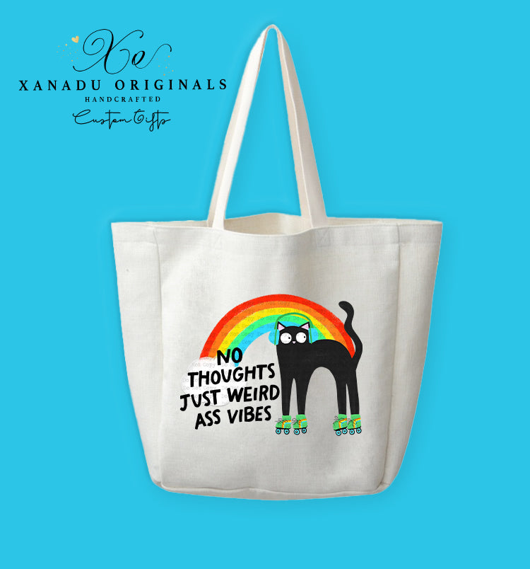 A cream-colored polyester linen tote bag featuring a cartoon illustration of a wide-eyed black cat wearing blue headphones and green roller skates, gliding under a vibrant retro rainbow arch. Bold black text to the left reads "NO THOUGHTS JUST WEIRD ASS VIBES."