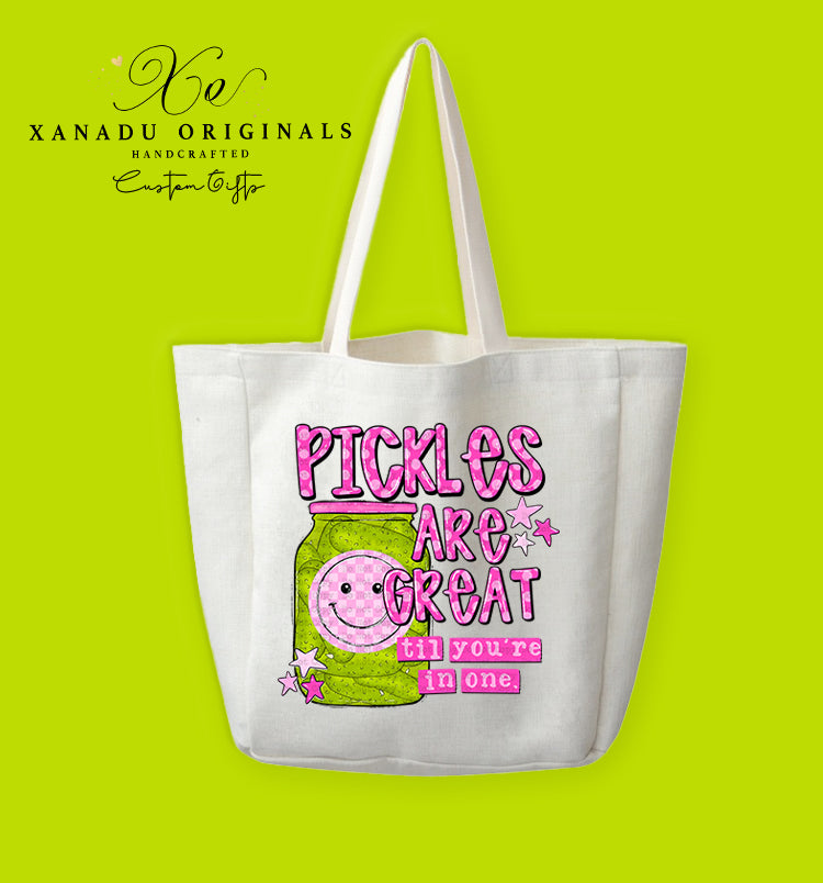 A cream-colored polyester linen tote bag featuring a bright pink retro graphic of a pickle jar with a pink smiley face next to the text "PICKLES ARE GREAT til you're in one".