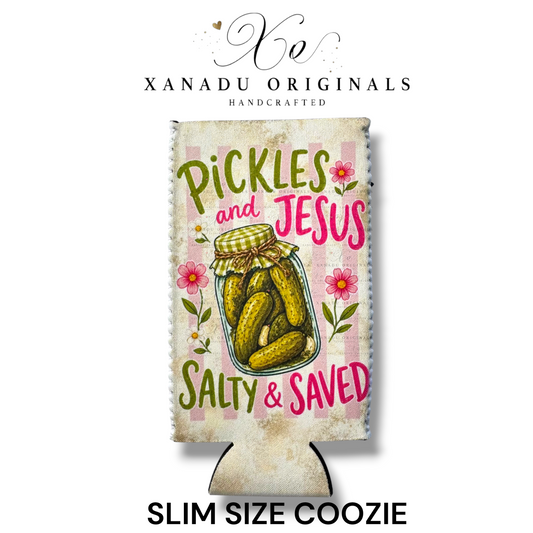 "Xanadu Originals handcrafted slim size neoprene can coozie featuring a rustic mason jar of dill pickles with the text 'Pickles and Jesus Salty & Saved' against a pink and white striped background with flowers."