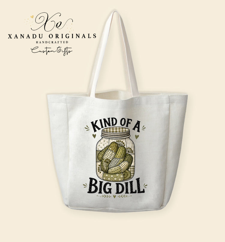 A cream-colored polyester linen tote bag featuring a digital illustration of a faux quilted patchwork mason jar filled with patterned green pickles between the text "KIND OF A BIG DILL".