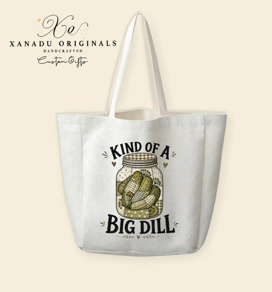 A cream-colored polyester linen tote bag featuring a digital illustration of a faux quilted patchwork mason jar filled with patterned green pickles between the text "KIND OF A BIG DILL".