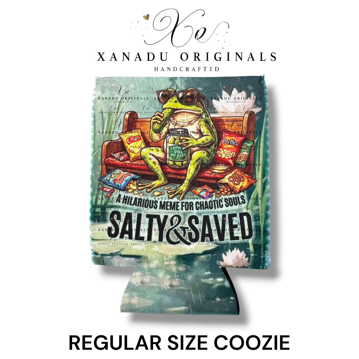 "Xanadu Originals handcrafted regular size neoprene can coozie featuring a detailed swamp illustration of a green frog wearing sunglasses on a wooden bench eating pickles and chips with the text 'A HILARIOUS MEME FOR CHAOTIC SOULS' and 'SALTY & SAVED'."