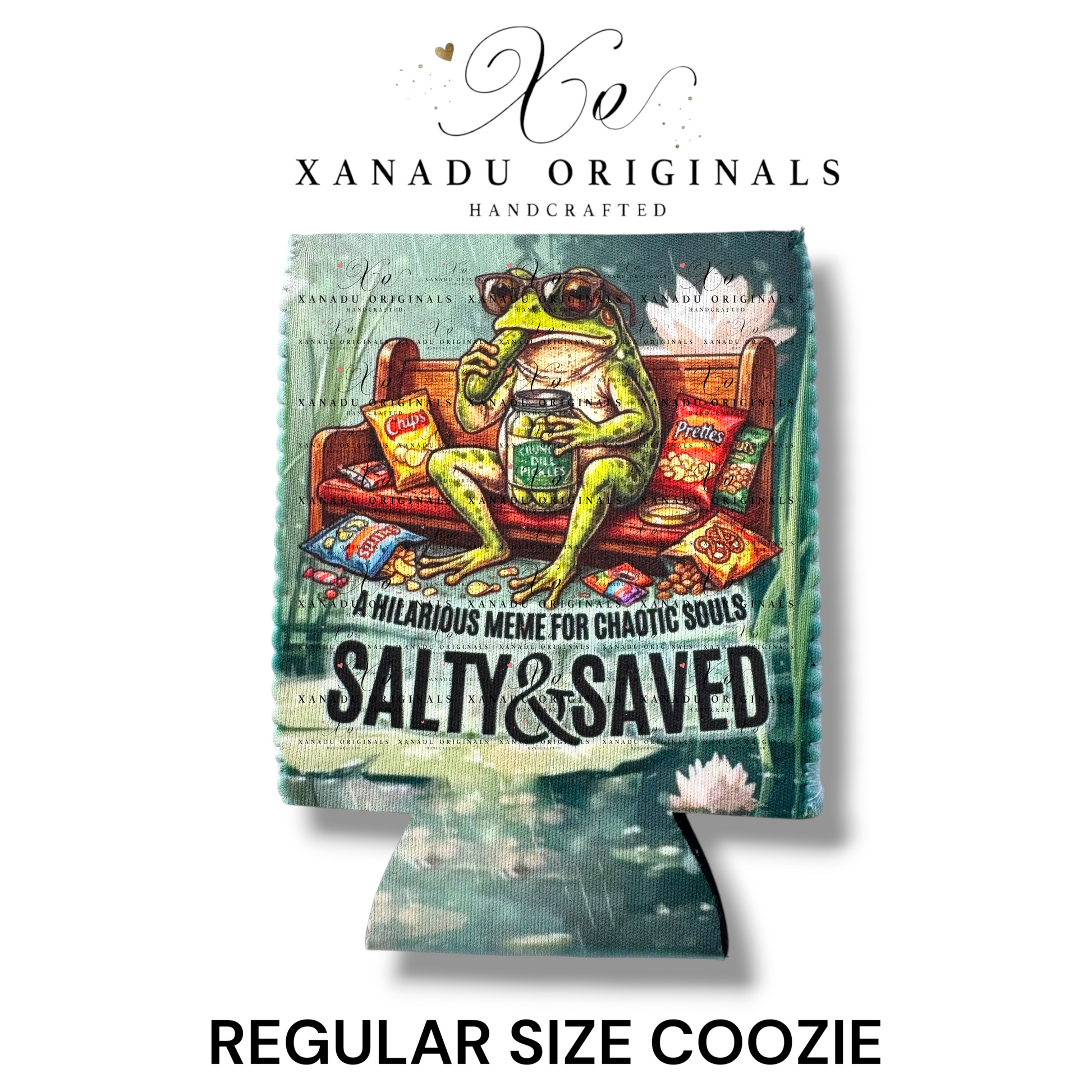 "Xanadu Originals handcrafted regular size neoprene can coozie featuring a detailed swamp illustration of a green frog wearing sunglasses on a wooden bench eating pickles and chips with the text 'A HILARIOUS MEME FOR CHAOTIC SOULS' and 'SALTY & SAVED'."
