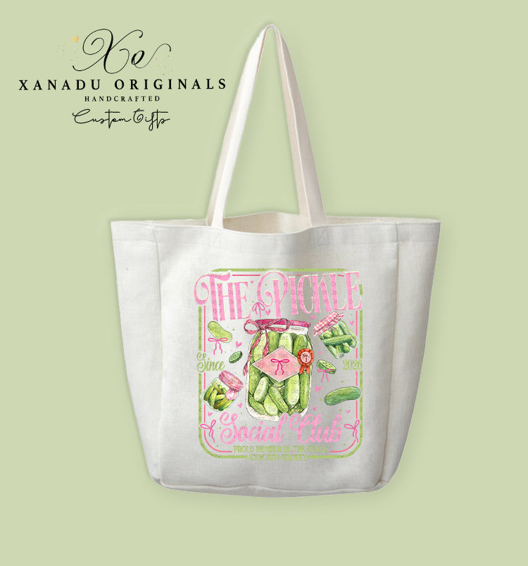 A cream-colored polyester linen tote bag featuring a watercolor pink and green country club aesthetic illustration of pickle jars with bows and text that reads "THE PICKLE Social Club".