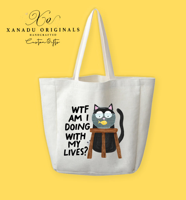A cream-colored polyester linen tote bag featuring a cartoon illustration of a wide-eyed black cat sitting behind a wooden stool with its head inside a clear glass fishbowl that has a single yellow fish. To the left, bold black text reads "WTF AM I DOING WITH MY LIVES?".